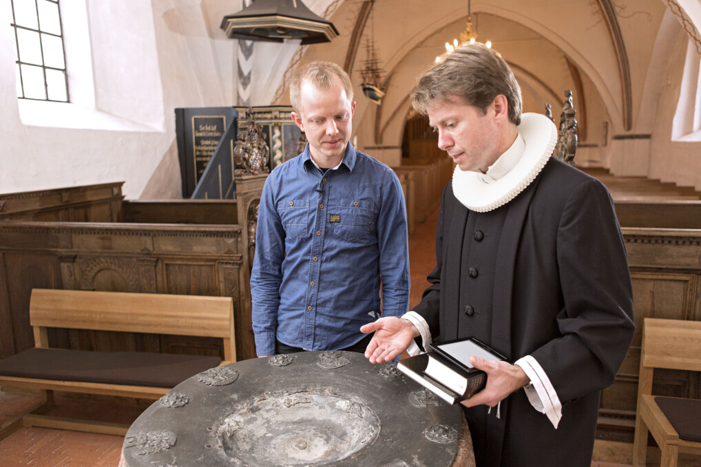 En præst og studerende ved en døbefont